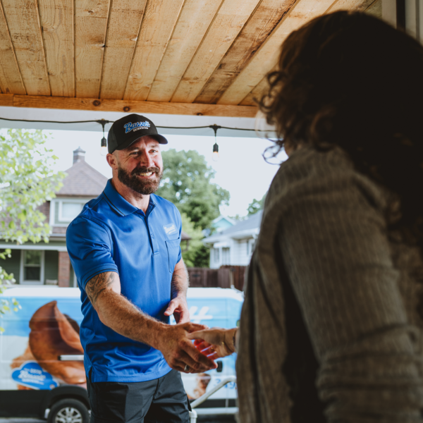 Bassett Services technician shaking hands with a homeowner at her front door