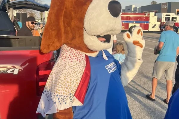 Bassett's hound dog mascot in a sparkly vest greeting visitors at a Trunk or Treat event